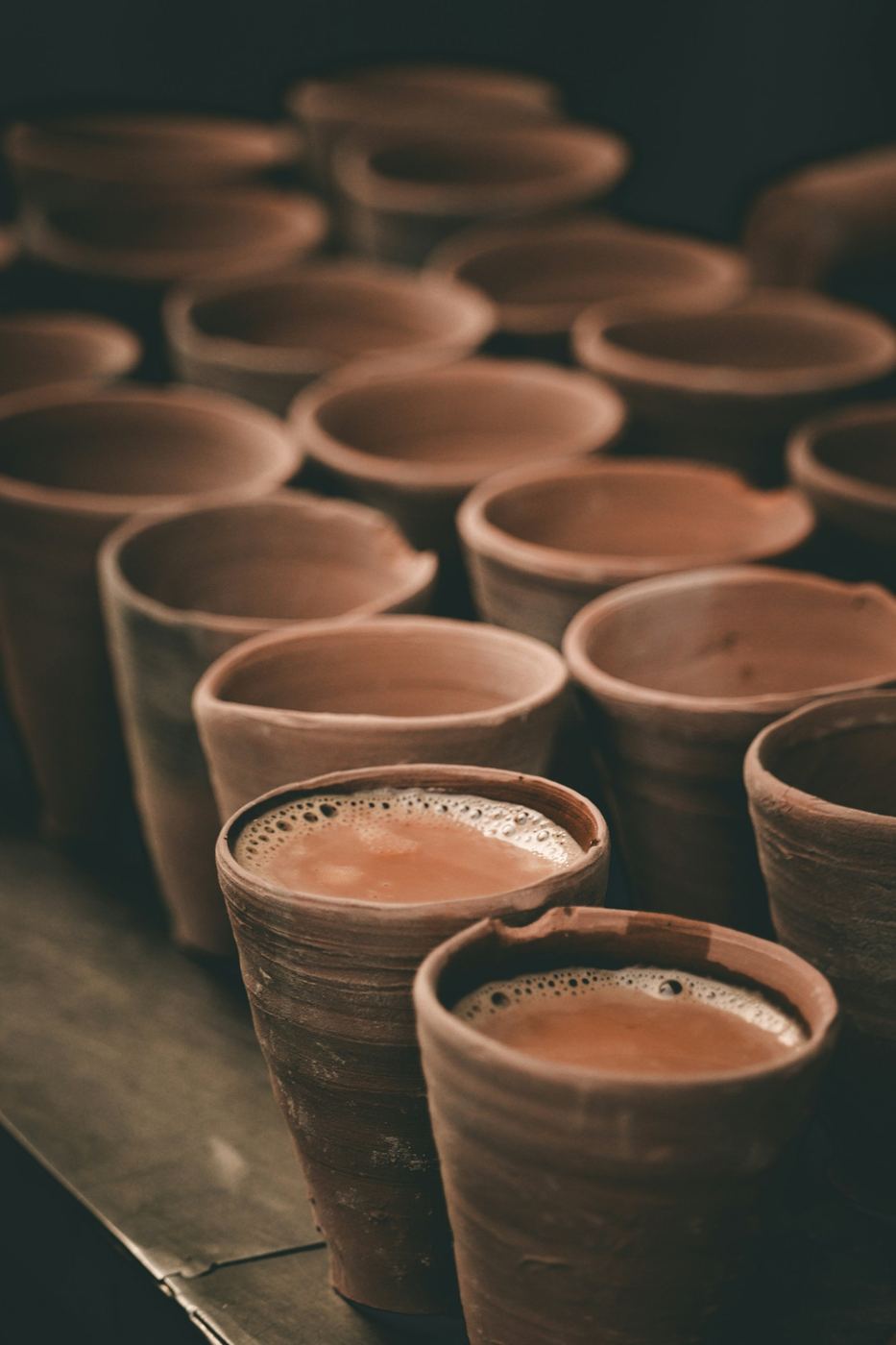 Rows of clay kulhads, two filled with chai