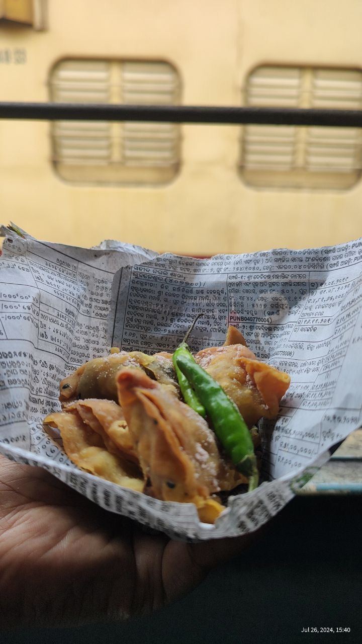 Samosas and a green chilli wrapped in newspaper